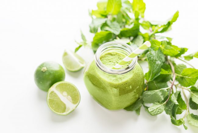 Green healty drink in mason jar with green fresh mint and lime on white background. Vegetarian food concept. Detox