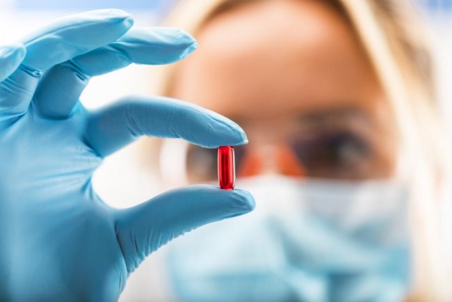 Doctor holding up a red pill Chemotherapy can help treat your cancer, but it has many side effects.